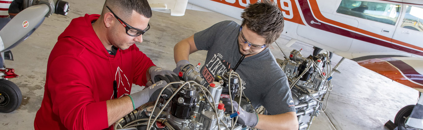 Two students work on an airplane engine