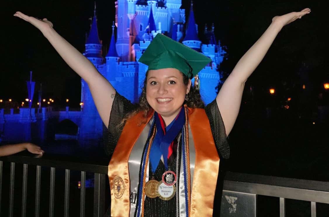 Angelina posing at Magic Kingdom with her arms up wearing EFSC regalia, and honors cords
